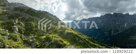 Panoramic view of summer landscape in the Suisse Alps with fresh green mountain pastures and old stone hut Panoramic view of summer landscape in the Suisse Alps with fresh green mountain pastures and old stone hut 128929222