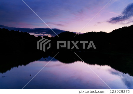 Beautiful sunset at Nunome Dam in Nara in the summer of 2025. Sunset clouds floating in the blue moment sky. Sky above Nunome Lake ② Beautiful sunset at Nunome Dam in Nara in the summer of 2025. Sunset clouds floating in the blue moment sky. Sky above Nunome Lake ② 128929275