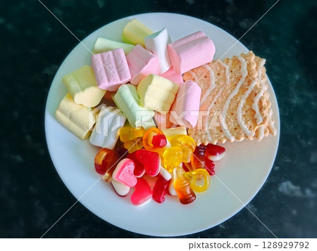 colorful candy in white plate. on black floor. plate with different sweets. 128929792