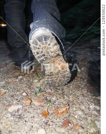 Person's foot is on a dirt path with leaves and rocks Person's foot is on a dirt path with leaves and rocks 128930022