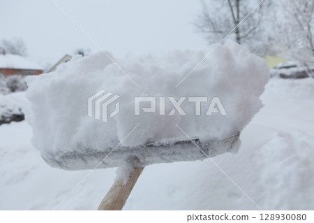 Snow shovel is holding a large pile of snow Snow shovel is holding a large pile of snow 128930080