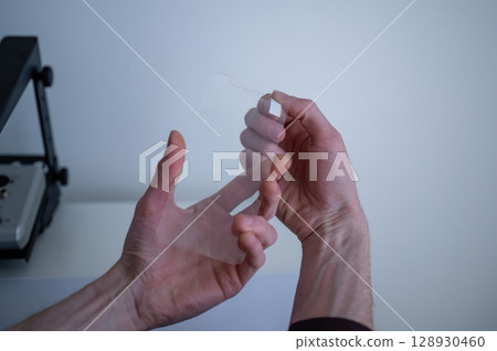 Man holding transparent smartphone screen protector before installation 128930460