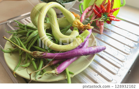 Unusually shaped vegetables on plate. Zucchini and eggplant, asparagus beans and peppers. Seasonal food and farm organic produce. 128932102