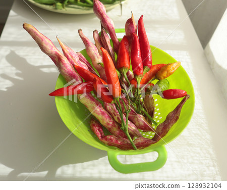 Bunch of red peppers and pink beans in green colander. Seasonal food and farm organic produce.  128932104