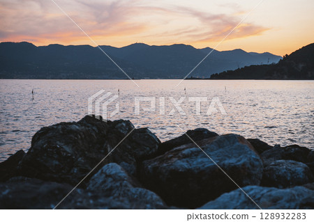 Rocky Lakeside Against Mountain Sunset Scenery Rocky Lakeside Against Mountain Sunset Scenery 128932283