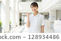 Smiling Asian nurse giving a thumbs up 128934486