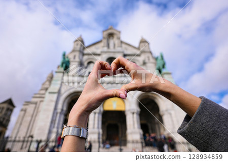 Hands forming heart shape with Sacre Coeur basilica behind 128934859