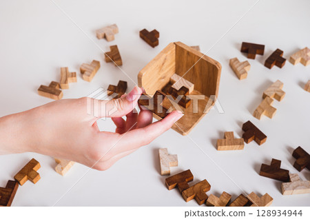 Female hand holding wooden puzzle for leisure thinking game Female hand holding wooden puzzle for leisure thinking game 128934944