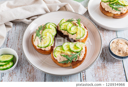 Appetizing sandwiches with cod liver pate, cucumber and arugula on a plate web banner Appetizing sandwiches with cod liver pate, cucumber and arugula on a plate web banner 128934966