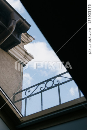 Skylight with sky view and balcony. The window offers a view of overcast sky with a few clouds. Skylight with sky view and balcony. The window offers a view of overcast sky with a few clouds. 128935576