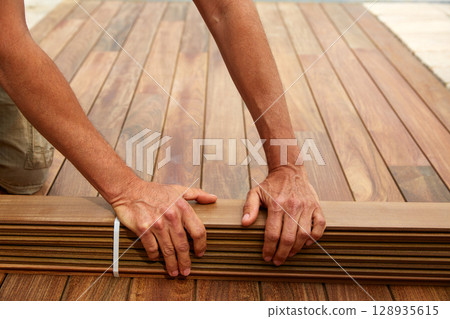 Ipe deck installation carpenter hands holding wood 128935615
