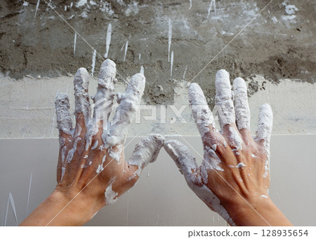 Astist plastering man hands with cracked plaster 128935654