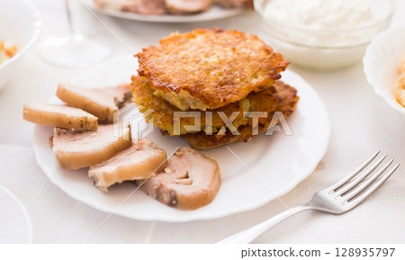 Fried grated potato pancakes with meat on white plate 128935797