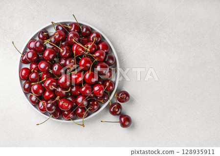 Black plate full of fresh ripe red sweet cherry on light gray textured bakground with copy space Black plate full of fresh ripe red sweet cherry on light gray textured bakground with copy space 128935911
