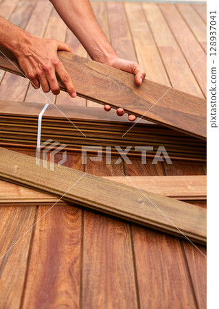 Ipe deck installation carpenter hands holding wood Ipe deck installation carpenter hands holding wood 128937041