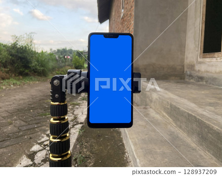 Smartphone with blue screen on the background of a brick wall. Smartphone with blue screen on the background of a brick wall. 128937209