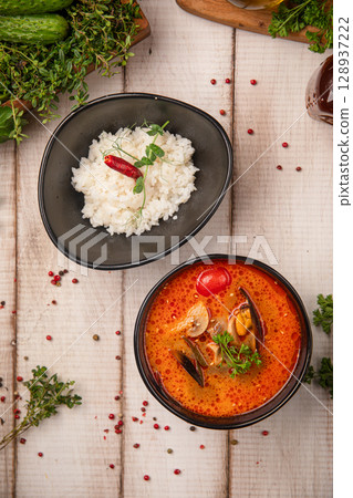 Spicy tom yum soup with seafood and bowl of rice 128937222