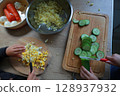 two child's hands cutting vegetables for salad close up 128937932
