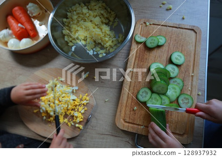 two child's hands cutting vegetables for salad close up 128937932