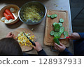 two child's hands cutting vegetables for salad close up 128937933