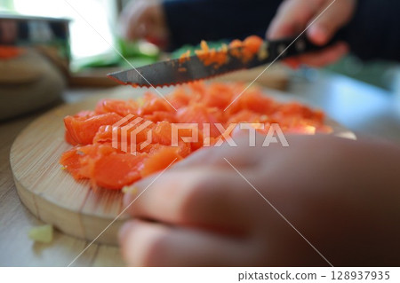 two child's hands cutting vegetables for salad close up two child's hands cutting vegetables for salad close up 128937935