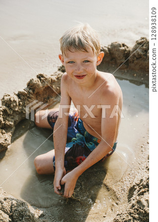 Boy Enjoying Sand Play in Beach Water Boy Enjoying Sand Play in Beach Water 128938109