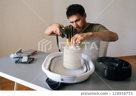 Front view of man cleaning humidifier filter using steam cleaner, removing dust and maintaining indoor air quality, thorough sanitizing technique. Concept of maintenance modern home appliance. 128938755