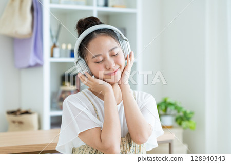 Young woman listening to music at home 128940343