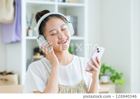 Young woman listening to music at home 128940346