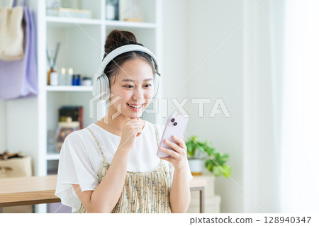 Young woman listening to music at home 128940347