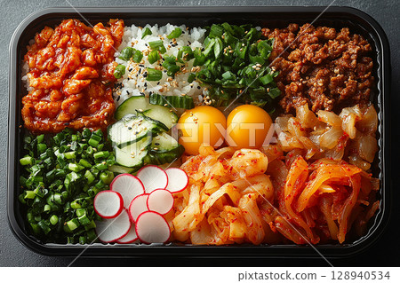 Korean-style lunch box with bibimbap ingredients, kimchi and pickled radish. Container with dosirak. 128940534