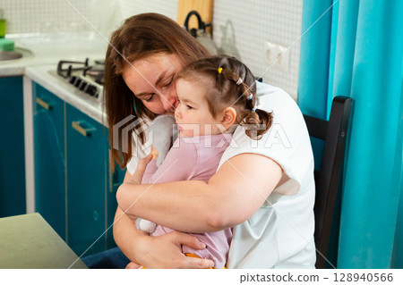 Child care provider embraces a preschool girl while building emotional intelligence and trust through physical affection and nurturing verbal interaction. Child care provider embraces a preschool girl while building emotional intelligence and trust through physical affection and nurturing verbal interaction. 128940566