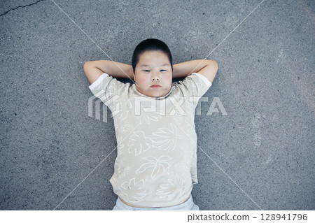Daydreaming under the sky Calm child, Asian teen boy stares upward lying on ground 128941796
