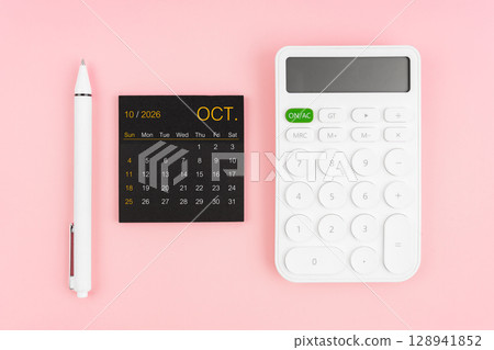 October 2026 calendar and white calculator with pen on pink color background. October 2026 calendar and white calculator with pen on pink color background. 128941852