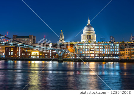 An enchanting evening view of Millennium Bridge spans the River Thames. Illuminated St. Paul's Cathedral stands majestically against the night sky in London. An enchanting evening view of Millennium Bridge spans the River Thames. Illuminated St. Paul's Cathedral stands majestically against the night sky in London. 128942068