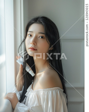 A young woman standing at the window A young woman standing at the window 128943015