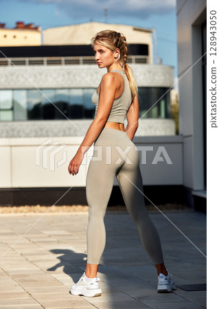 Athletic woman posing outdoors in a serene urban setting Athletic woman posing outdoors in a serene urban setting 128943050