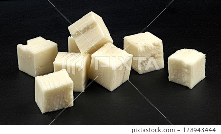 Cubes of white cheese isolated on black background, copy space 128943444
