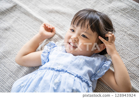 A little girl lying on the floor laughing 128943924