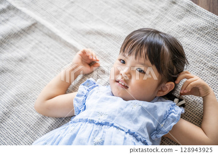 A little girl lying on the floor laughing 128943925