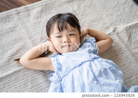 A little girl lying on the floor laughing 128943926