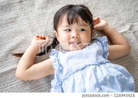 一個小女孩躺在地板上笑 一個小女孩躺在地板上笑 128943928