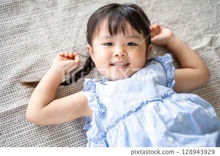 一個小女孩躺在地板上笑 128943929