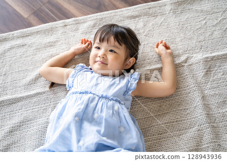 一個小女孩躺在地板上笑 一個小女孩躺在地板上笑 128943936
