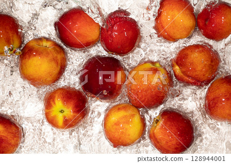 Vibrant Peaches in Water with Splash. Summer Fruit Scene. 128944001