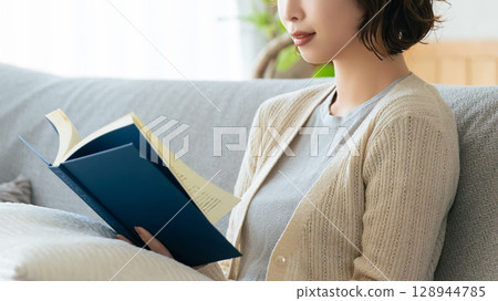 A woman sitting on a sofa and reading A woman sitting on a sofa and reading 128944785