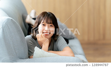 說謊在沙發的一名微笑的婦女 128944787