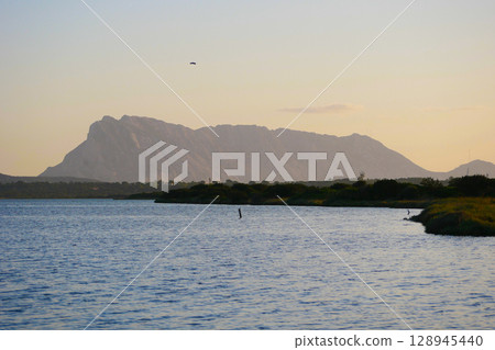 Scenic view of a mountainous landscape with a lake in the foreground during the sunset in San Teodoro, Sardinia, Italy Scenic view of a mountainous landscape with a lake in the foreground during the sunset in San Teodoro, Sardinia, Italy 128945440