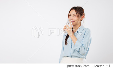 Woman drink liquid water clear fresh, young Asian hold transparent glass of clean water, face portrait showing beautiful proper nutrition healthy lifestyle, drinking regime, isolated white background 128945981