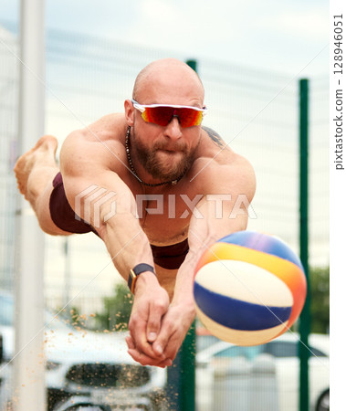 Athletic volleyball player diving for a ball in an intense action moment 128946051